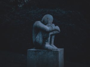Statue, Mann, der seine Knie umarmt